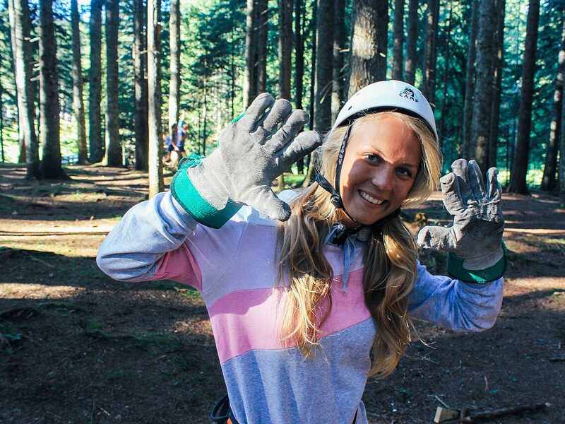 A zipline rider in a helmet in the forest